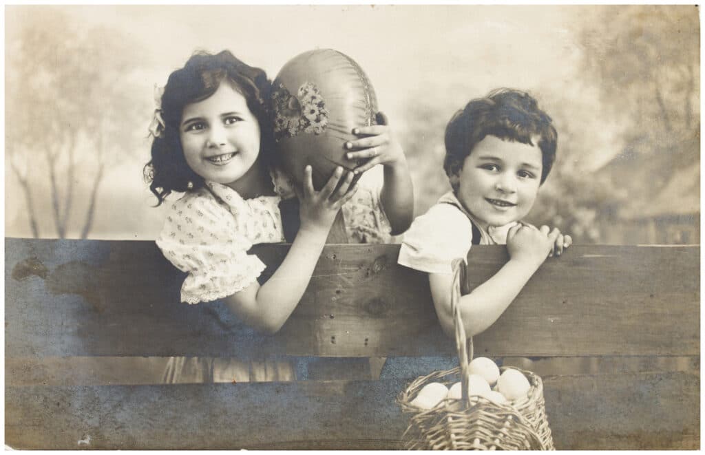 Black and white photo of two little kids on a fence
