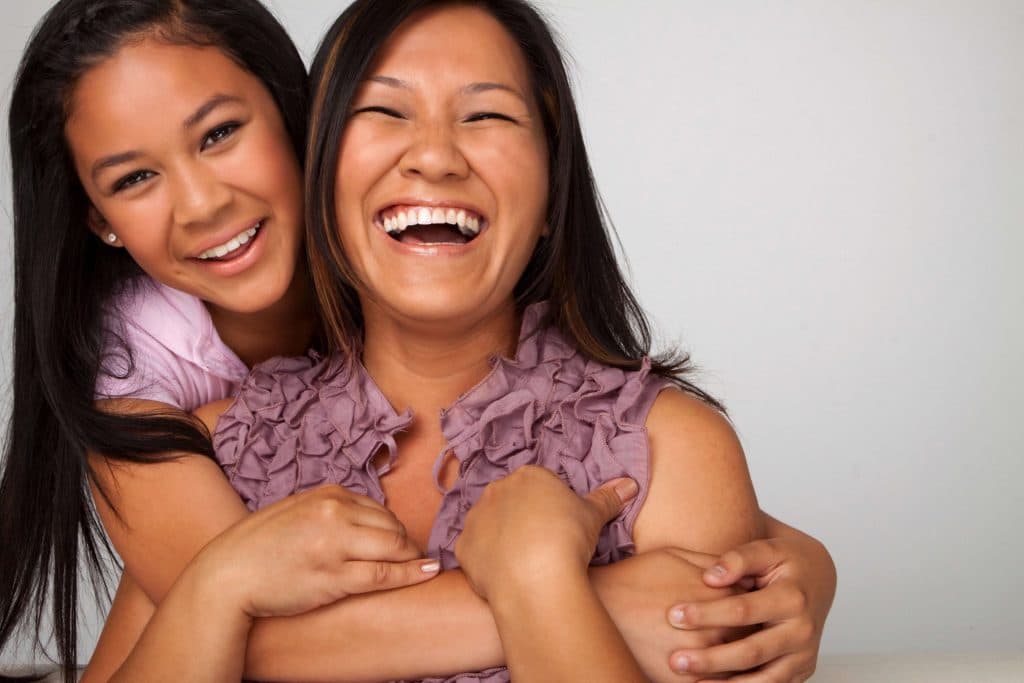Mother and daughter hugging and smiling at the camera