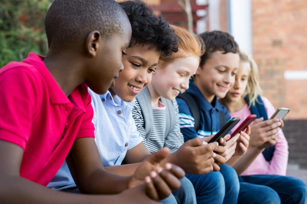 row of young kids smiling at phones
