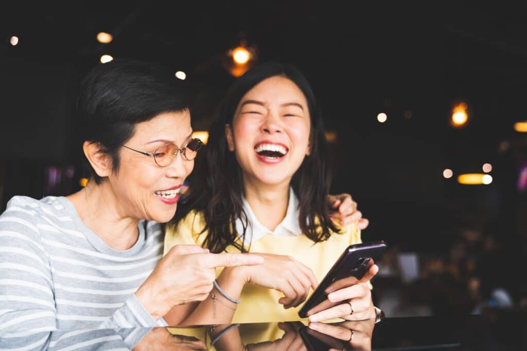 mother and daughter looking at cellphone and laughing