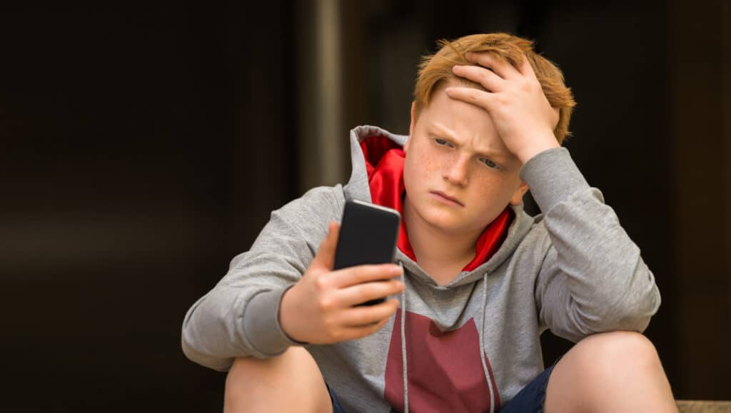 teen boy looks concerned at his phone