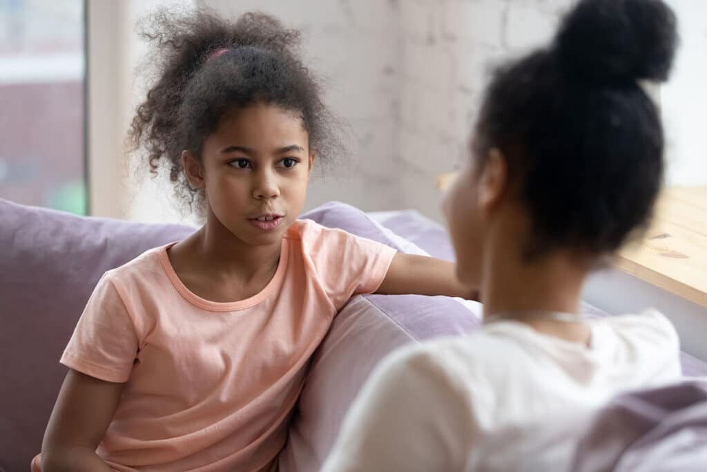 young girl talking to her mom on a couch