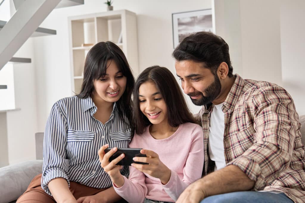 mother, father, and daughter looking at smartphone