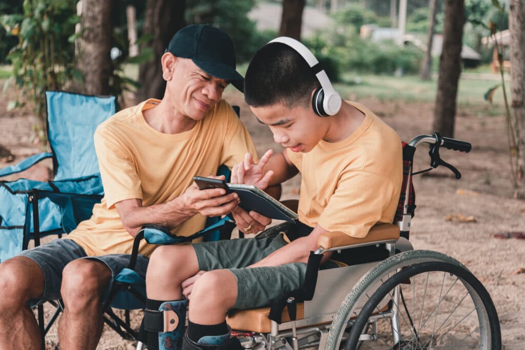 father looking at tech with son in wheelchair