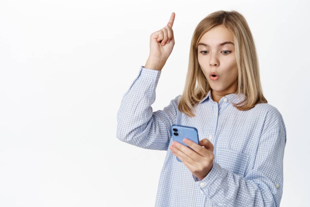 young girl holding cellphone holding finger in the air
