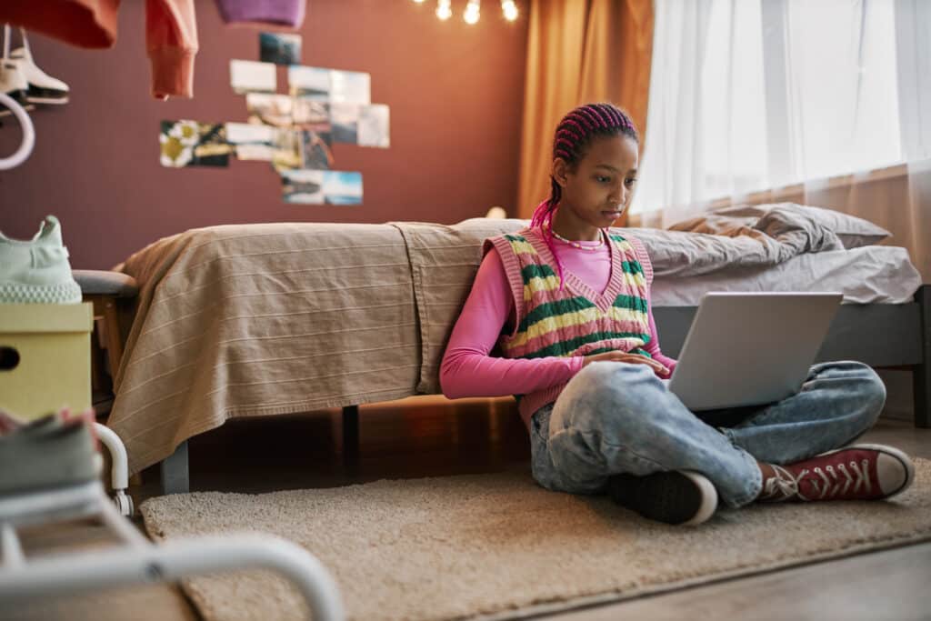 teen girl on laptop on floor of her bedroom