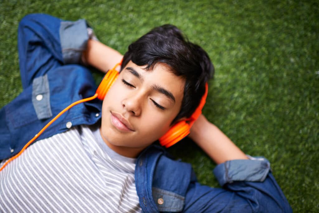 boy listening to headphones laying in the grass