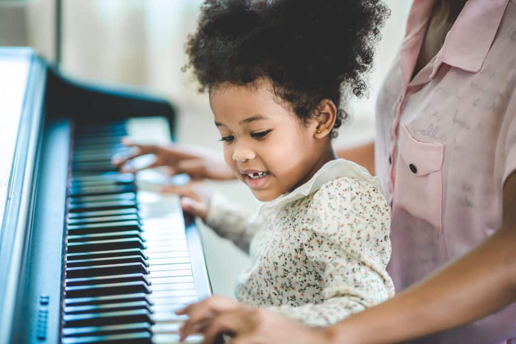 little girl teaching mother piano