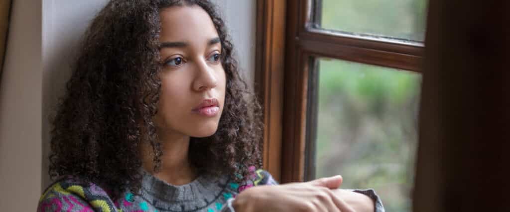 sad teen girl looking out window