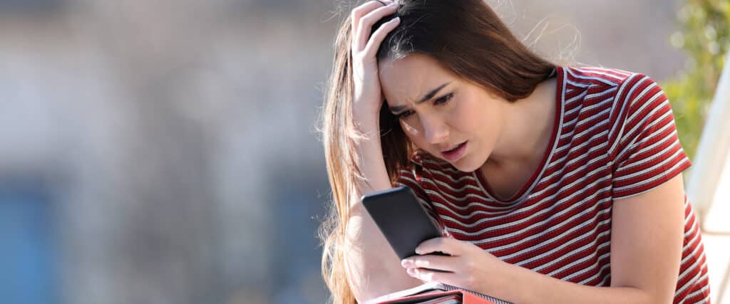 upset teen looking at phone