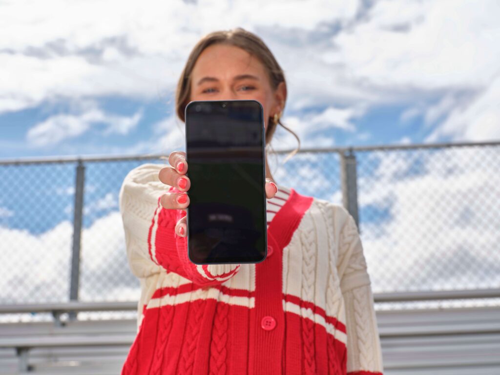 teen girl holding smartphone over her face