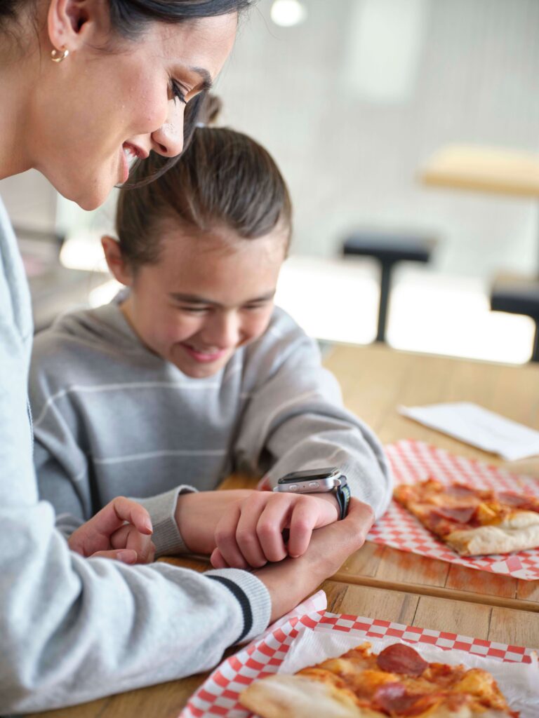 mom and daughter smiling at smart watch for kids