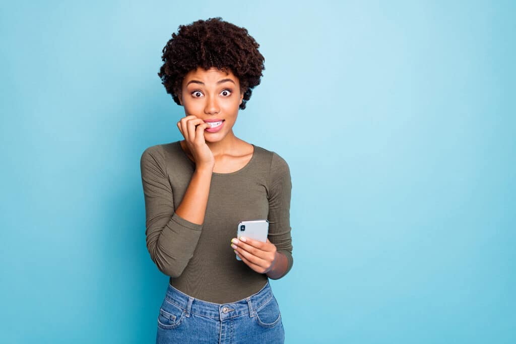 women biting her nails with cell phone in hand