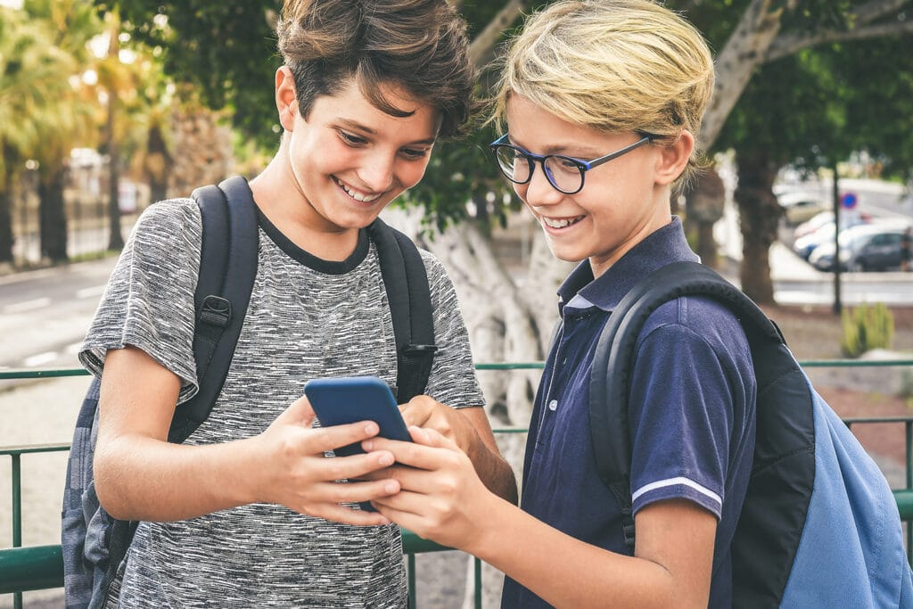 two young boys smiling at smart phone