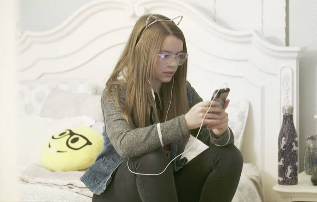 Girl sitting on bed using her no internet phone