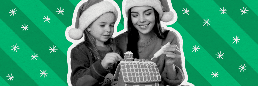 mom and daughter wearing santa hats building gingerbread house together