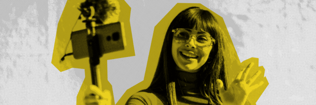 influencer waving to a cell phone on a selfie stick