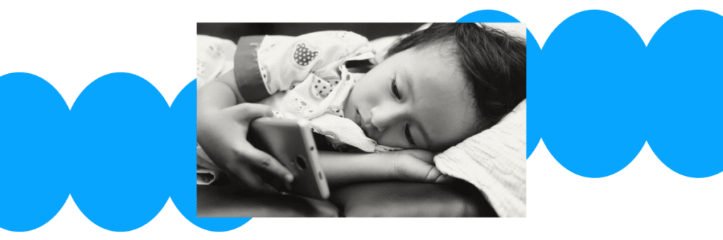 little girl laying on her side looking at smartphone