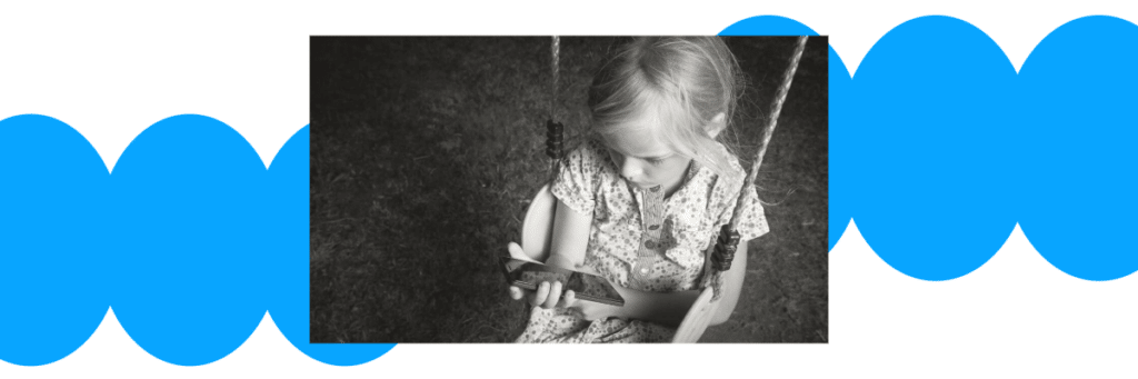 sad little girl on swing looking at smartphone