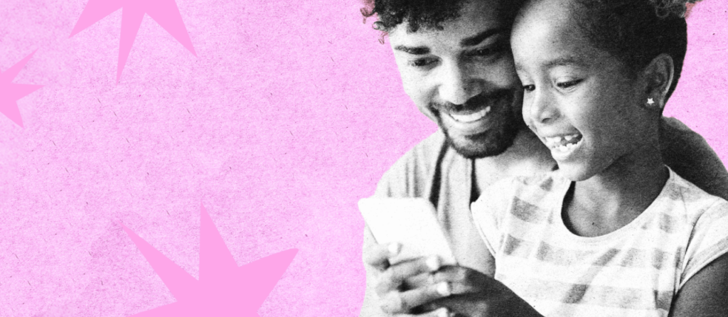 A dad and his daughter looking at a phone together and smiling