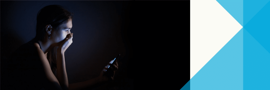 teen looking at phone with hand covering mouth