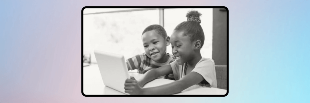 two little kids smiling at a tablet